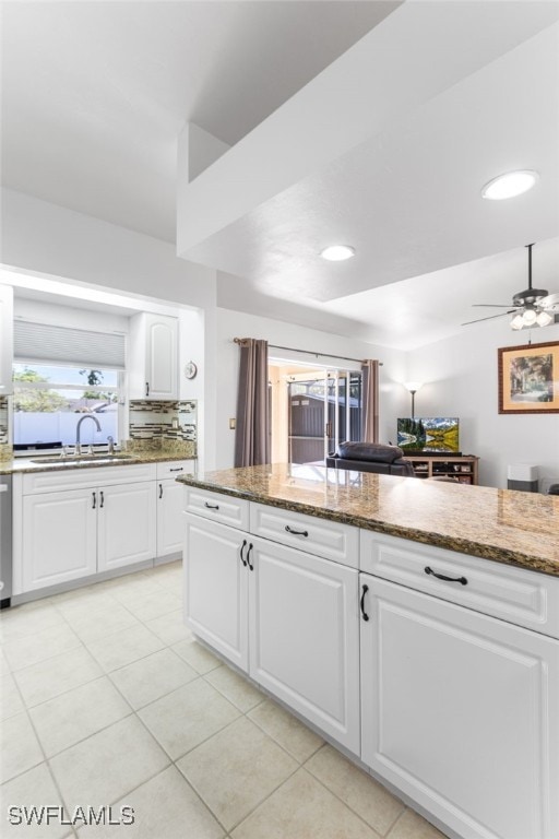 kitchen featuring stone countertops, sink, white cabinets, light tile patterned floors, and ceiling fan