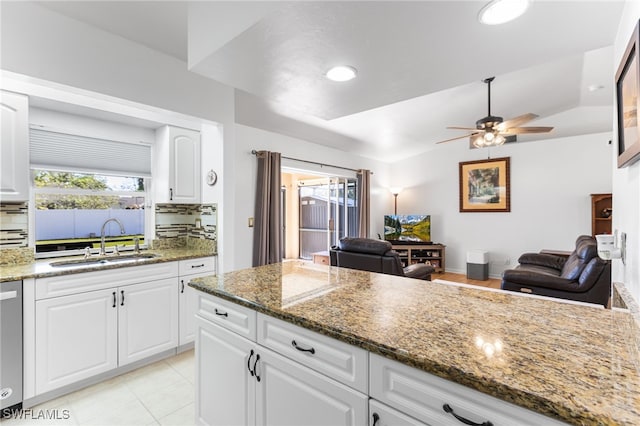 kitchen with backsplash, dark stone countertops, sink, and white cabinets