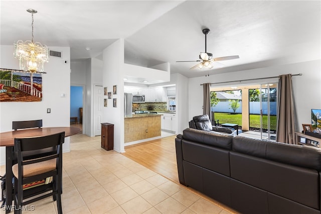 tiled living room featuring lofted ceiling and ceiling fan with notable chandelier