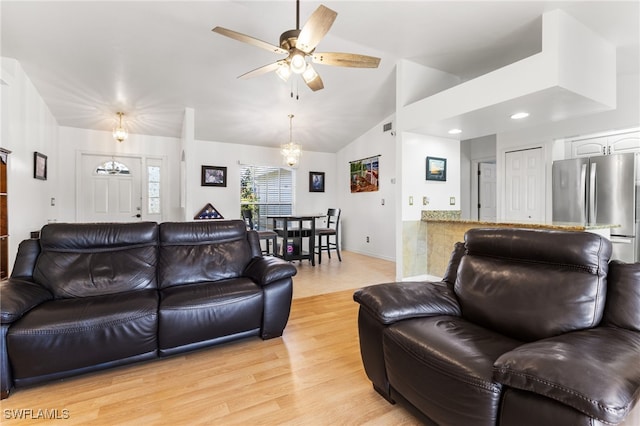 living room with ceiling fan with notable chandelier, vaulted ceiling, and light hardwood / wood-style floors