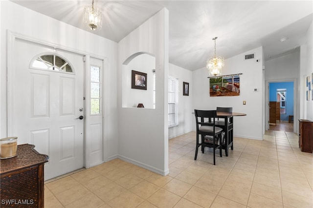 entryway with vaulted ceiling, light tile patterned floors, and a notable chandelier