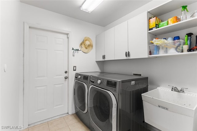 clothes washing area with cabinets, light tile patterned flooring, sink, and washing machine and clothes dryer