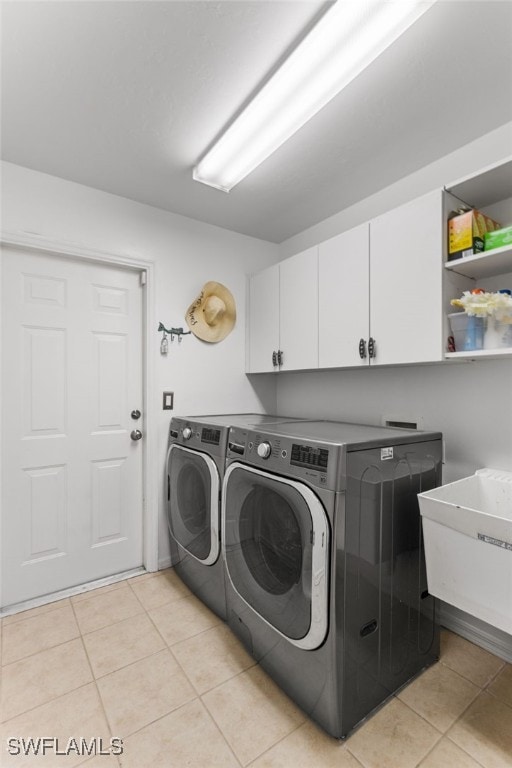 laundry room featuring light tile patterned floors, sink, washer and clothes dryer, and cabinets