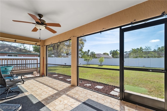 unfurnished sunroom with ceiling fan