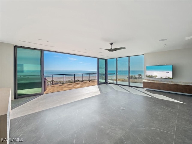 unfurnished living room with expansive windows and ceiling fan