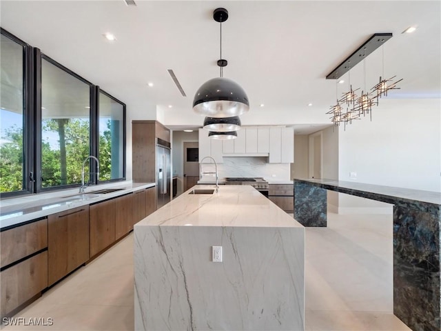 kitchen with light stone counters, decorative light fixtures, appliances with stainless steel finishes, a large island, and white cabinets