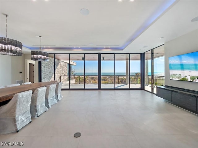 interior space with a notable chandelier, a tray ceiling, and a wall of windows