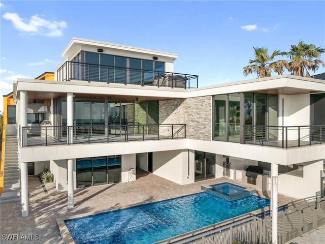 back of property with a pool with hot tub, a patio, and a balcony