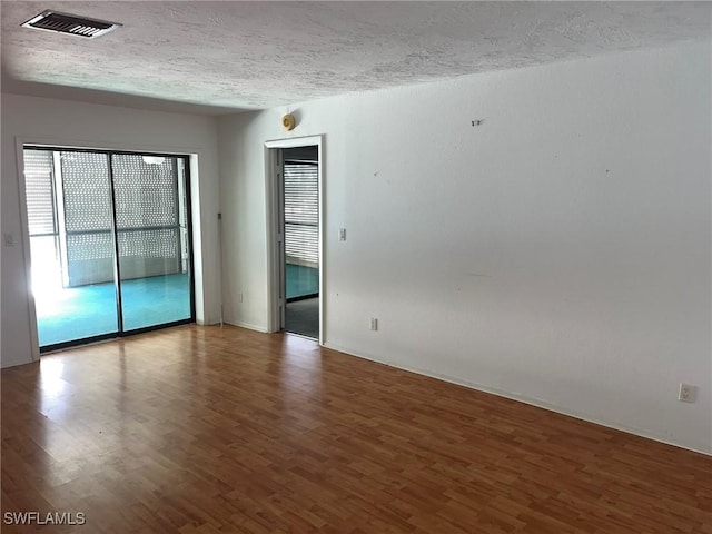 empty room with wood-type flooring and a textured ceiling