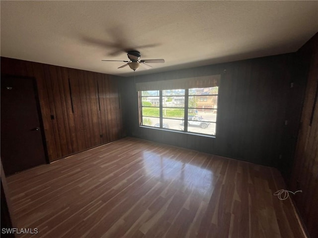21551 Madera Rd, Fort Myers Beach, FL 33931 - empty room with wood finished floors, ceiling fan, wooden walls, and a textured ceiling