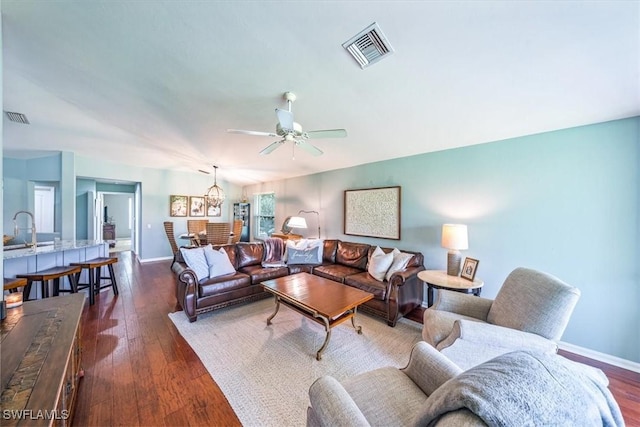 living room featuring ceiling fan, sink, and dark hardwood / wood-style flooring