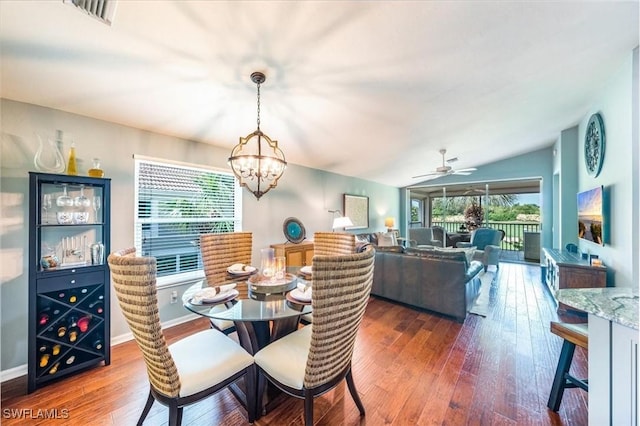 dining area with a healthy amount of sunlight, lofted ceiling, dark wood-type flooring, and ceiling fan with notable chandelier