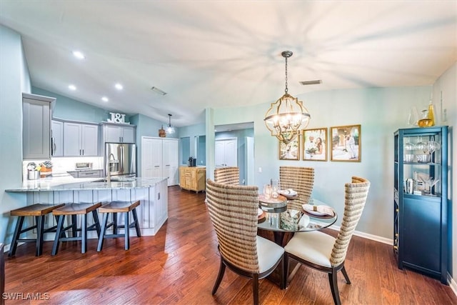 dining room with dark hardwood / wood-style flooring, sink, vaulted ceiling, and an inviting chandelier