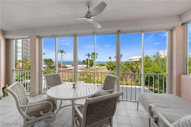 sunroom featuring a water view and ceiling fan