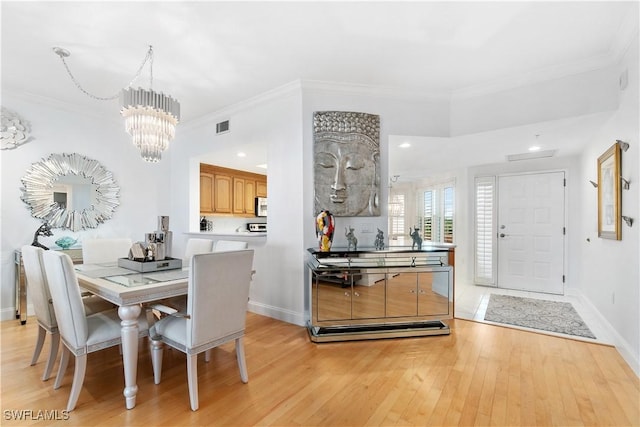 dining room featuring crown molding, a chandelier, and light wood-type flooring