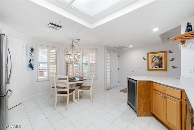 kitchen with pendant lighting, light tile patterned floors, stainless steel fridge, an inviting chandelier, and beverage cooler