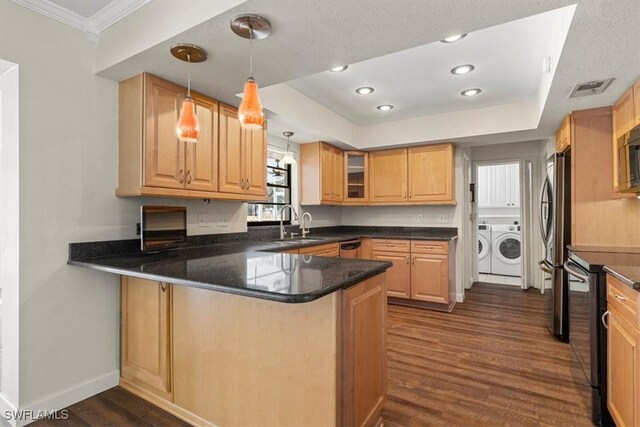 kitchen with dark wood-type flooring, kitchen peninsula, pendant lighting, independent washer and dryer, and stainless steel appliances