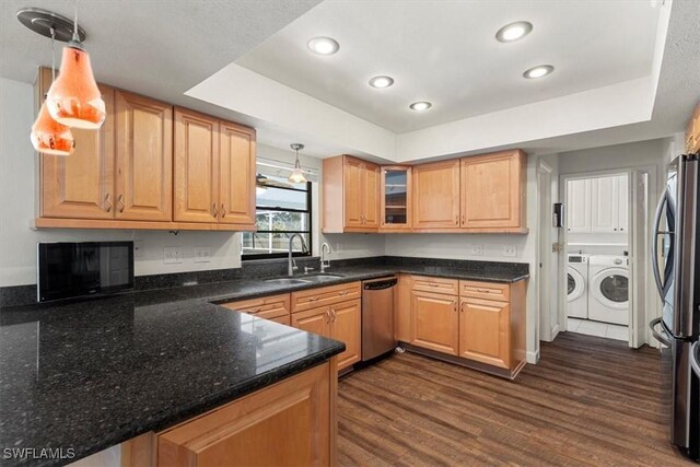 kitchen with sink, washer and clothes dryer, hanging light fixtures, stainless steel appliances, and a raised ceiling