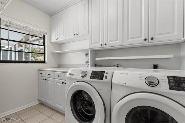 laundry area with cabinets, light tile patterned floors, and washer and dryer