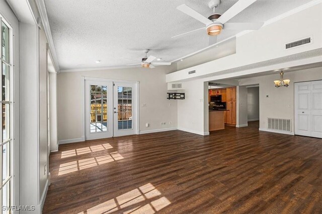 unfurnished living room featuring dark wood-type flooring, a textured ceiling, ceiling fan with notable chandelier, vaulted ceiling, and french doors