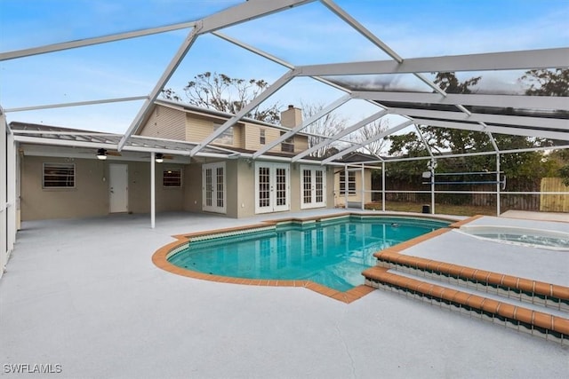 view of swimming pool with an in ground hot tub, a lanai, a patio area, and french doors