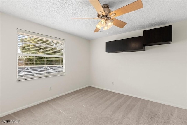 carpeted spare room featuring ceiling fan and a textured ceiling