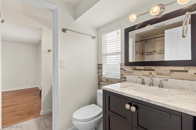 bathroom featuring tile patterned floors, vanity, toilet, and decorative backsplash