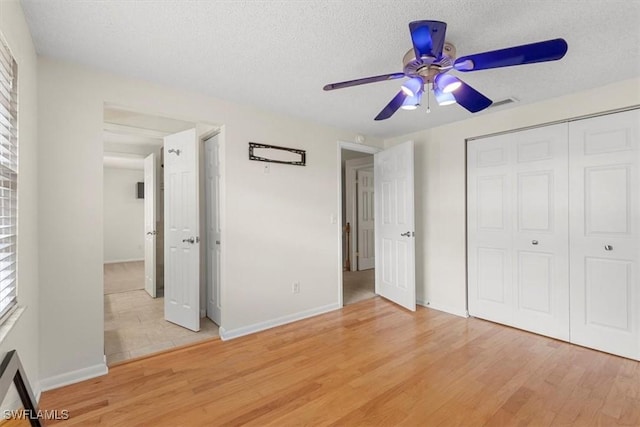 unfurnished bedroom with ceiling fan, light hardwood / wood-style floors, a closet, and a textured ceiling