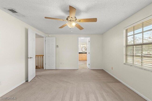 carpeted empty room featuring ceiling fan and a textured ceiling