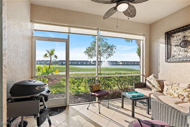 sunroom featuring a water view and ceiling fan