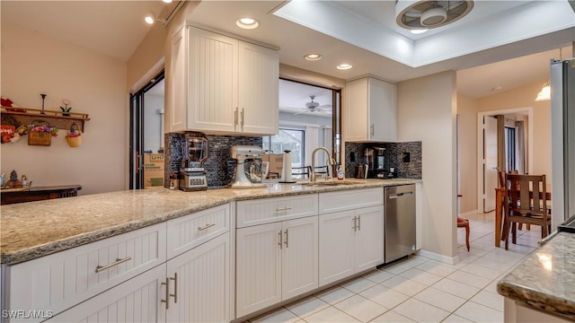 kitchen with sink, stainless steel dishwasher, white cabinets, and light tile patterned floors