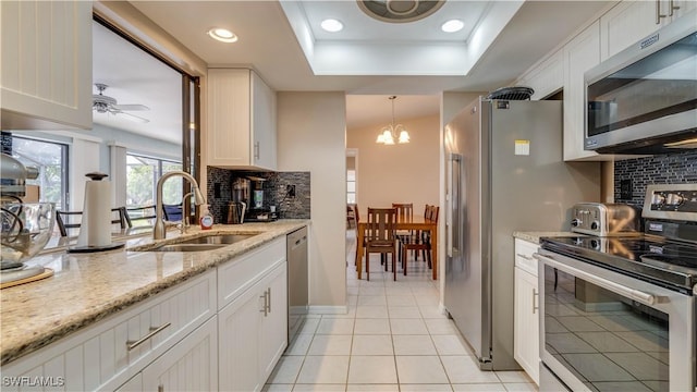 kitchen featuring pendant lighting, sink, appliances with stainless steel finishes, light stone countertops, and white cabinets