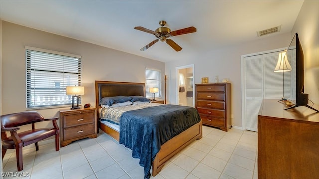 tiled bedroom featuring multiple windows, connected bathroom, ceiling fan, and a closet