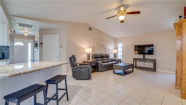 living room featuring vaulted ceiling, light tile patterned floors, and ceiling fan