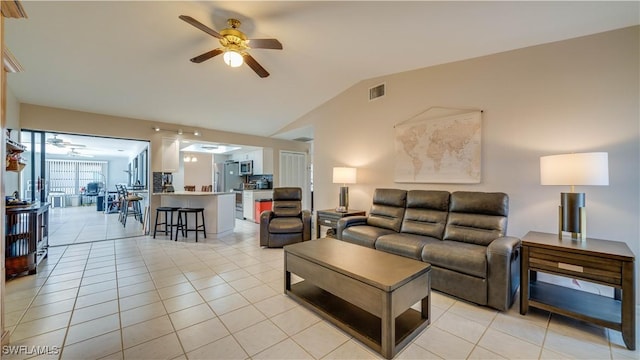 living room featuring lofted ceiling, light tile patterned floors, and ceiling fan