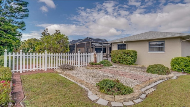 view of front of home featuring glass enclosure and a front yard