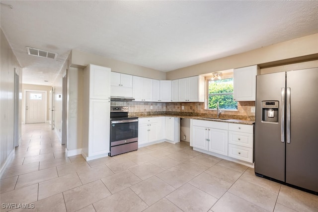 kitchen with white cabinetry, sink, dark stone countertops, decorative backsplash, and stainless steel appliances