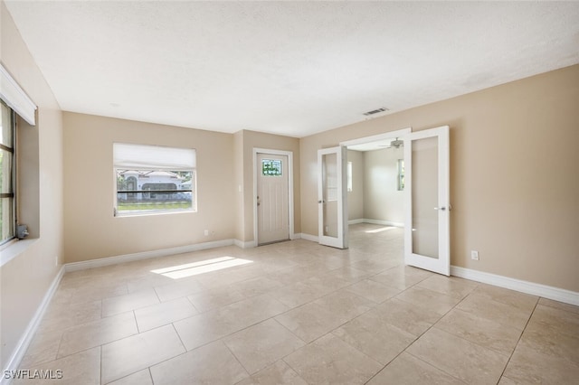 unfurnished room with light tile patterned floors and french doors