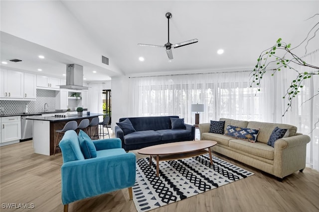 living room with ceiling fan, lofted ceiling, sink, and light hardwood / wood-style floors