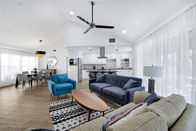 living room with ceiling fan, high vaulted ceiling, and light hardwood / wood-style floors