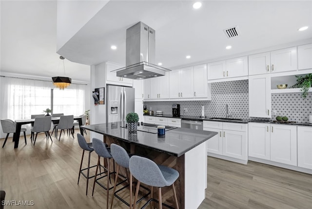 kitchen featuring sink, a center island, island exhaust hood, stainless steel appliances, and white cabinets