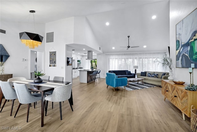 dining room with ceiling fan, high vaulted ceiling, and light hardwood / wood-style floors