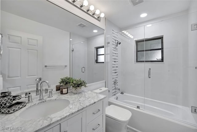 full bathroom featuring vanity, enclosed tub / shower combo, and toilet