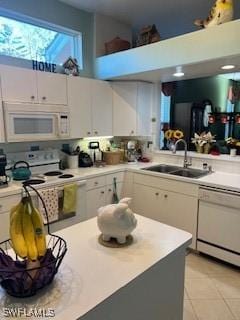 kitchen featuring sink, white appliances, white cabinets, and a high ceiling