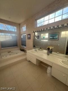 bathroom with plenty of natural light, tiled bath, tile patterned flooring, and vanity