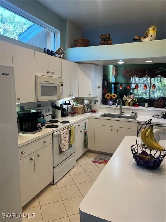 kitchen featuring light countertops, light tile patterned flooring, white cabinets, white appliances, and a sink