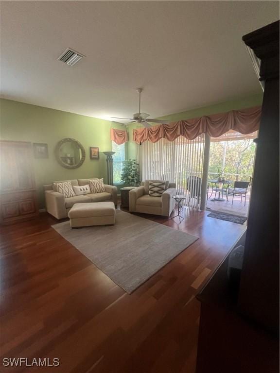 living room with ceiling fan, visible vents, and wood finished floors