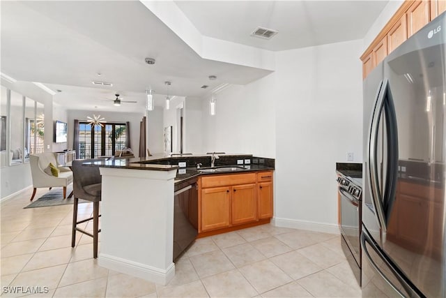 kitchen featuring a kitchen bar, sink, kitchen peninsula, pendant lighting, and black appliances