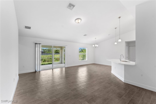 unfurnished living room with vaulted ceiling, sink, a notable chandelier, and dark hardwood / wood-style floors