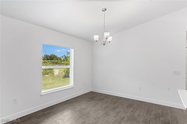 empty room with dark wood-type flooring and a notable chandelier